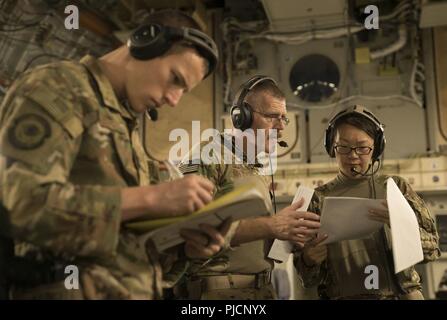 Senior Airman Kyle Caldwell, flight medic, left, Maj. Jeffery Carlson, medical crew director, and Capt. Isebell Zhang, flight nurse, review patient medical reports aboard a C-17 Globemaster III en route to Ramstein Air Base, Germany, July 21, 2018. The Airmen of the 455th Expeditionary Aeromedical Evacuation Squadron based at Bagram Airfield, Afghanistan, are tasked with transporting injured U.S. and NATO partner service members. Stock Photo