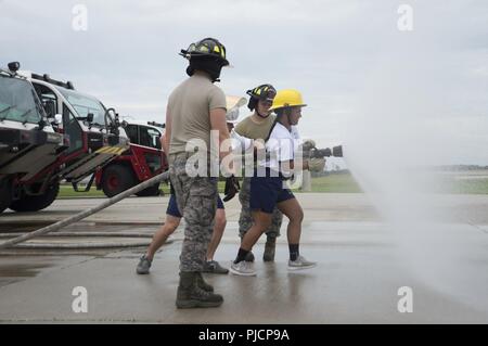 U.S. Air Force Fire Protection Airmen with the 6th Civil Engineer Squadron assist cadets in operating a fire hose at the Crash Fire Station on MacDill Air Force Base, Fla., July 6, 2018. As part of the Operations Air Force program, cadets received mentorship from enlisted and commissioned personnel, while experiencing multiple career fields and how each contributes to rapid global mobility. Stock Photo