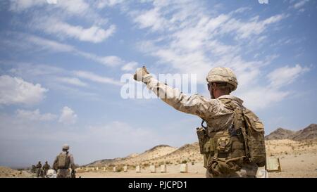 U.S. Marines and Sailors with 3rd Battalion, 6th Marine Regiment signal that the firing line is ready to fire during an M-240 B battle sight zero (BZO) range at Marine Corps Air Ground Combat Center Twentynine Palms, CA, on July 15, 2018. The purpose of this range is to ensure the accuracy of the machine guns in preparation for Integrated Training Exercise (ITX) 5-18. Stock Photo