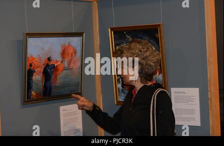 A visitor to the Coos History Museum looks at a piece of art from the Coast Guard Art Program, during the opening night of the gallery showcase in Coos Bay, Ore., July 19, 2018.    The Coast Guard Art Program uses fine art as an outreach tool for educating diverse audiences about the United States Coast Guard.    U.S. Coast Guard Stock Photo