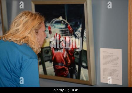 A visitor to the Coos History Museum looks at a piece of art from the Coast Guard Art Program, during the opening night of the gallery showcase in Coos Bay, Ore., July 19, 2018.    Fifteen pieces of art from 11 different artists will be on display at the Coos History Museum for nearly two months between the dates of July 19 and Sept. 16, 2018.    U.S. Coast Guard Stock Photo