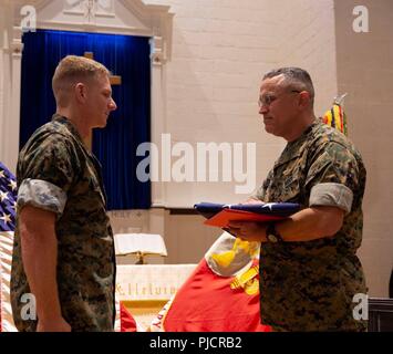 U.S. Navy Lt. Cmdr. Carl J Stamper receives the American Flag from 24th Marine Expeditionary Commanding Officer Col. Eric D. Cloutier, during his retirement ceremony on Marine Corps Base Camp Lejeune, North Carolina., July 19, 2018. Stamper is retiring after 20 years of honorable and faithful service in the United States Navy. Stock Photo