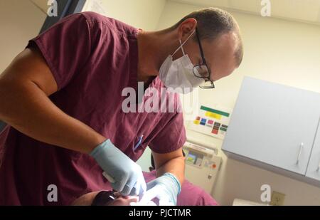 JACKSONVILLE, Fla. (July 24, 2018) Lt. Cameron McMillin, a dentist at Naval Hospital Branch Health Clinic Jacksonville, conducts an annual dental exam. McMillan, a native of Orlando Florida, says “We take care of the warfighters and make sure all the service members are ready to deploy or defend our freedoms.” The Navy Dental Corps celebrates its 106th birthday on Aug. 22, 2018 and continues to contribute to humanitarian missions around the world. Stock Photo
