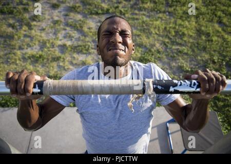 U.S. Air Force Airman 1st Class Quon Green, an entry controller assigned to the 6th Security Force Squadron, performs a pull up at MacDill Air Force Base, Florida, July 17, 2018. Over the last eight years, MacDill AFB has a zero percent wash out rate at the official Phoenix Raven Qualification Course at Joint Base McGuire-Dix-Lakehurst, N.J. because of their challenging Phoenix Ravens preparation course. Stock Photo