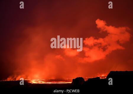 Glowing river of hot lava runs through Kapoho, Hawaii from the Kilauea Volcano east rift zone toward the ocean. Shimmering heat waves distort the view Stock Photo