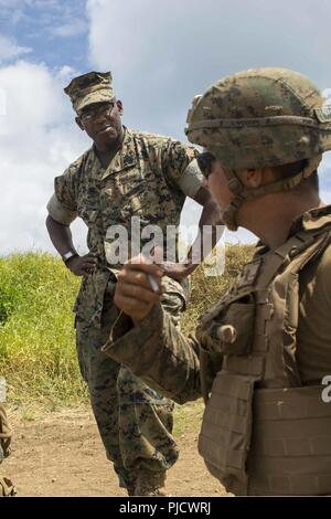 OAHU - U.S. Marine Sgt. Maj. Brian Priester, sergeant major of 13th Marine Expeditionary Unit (MEU), speaks with the Marines of Lima Company, Battalion Landing Team 3/1, 13th MEU, during a live fire training exercise at Marine Corps Base Hawaii, during sustainment training exercise, July 20, 2018. This training allowed Marines and Sailors to sustain skills developed during a comprehensive six-month predeployment training cycle, and included planning and executing ship-to-shore operations, company-sized helicopter and amphibious raids, combat marksmanship and convoy operations. The Essex Amphib Stock Photo