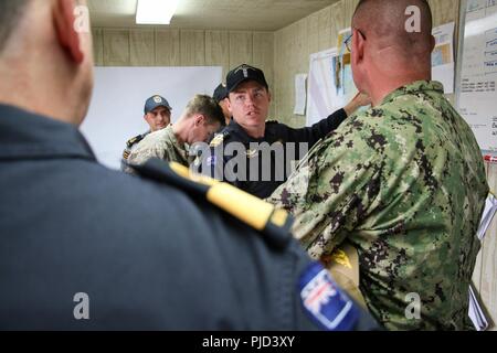 NAVAL BASE POINT LOMA, Calif.  (July 17, 2018) - Royal New Zealand Navy (RNZN) Lt. Cmdr. Ben Martin, undersea mine countermeasures commander for Rim of the Pacific (RIMPAC) exercise in the Southern California area of operations, briefs RNZN Commodore Tony Millar, maritime component commander and representative of the Chief of Navy (New Zealand), left, and U.S. Navy Rear Adm. Dave Welch, commander, Mine Warfare Task Force, right, during a visit onboard Naval Base Point Loma, July 17. Twenty-five nations, 46 ships, five submarines, about 200 aircraft and 25,000 personnel are participating in RIM Stock Photo