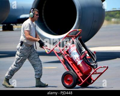 JOINT BASE PEARL HARBOR-HICKAM, Hawaii (July 16, 2018) - Tech. Sgt. Timothy Hardy, 507th Aircraft Maintenance Squadron crew chief from Tinker Air Force Base, Oklahoma, rolls a fire extinguisher into place near a 97th Air Mobility Wing KC-135 Stratotanker from Altus Air Force Base, Oklahoma, during the Rim of the Pacific (RIMPAC) exercise, July 16. Twenty-five nations, 46 ships, five submarines, and about 200 aircraft and 25,000 personnel are participating in RIMPAC from June 27 to Aug. 2 in and around the Hawaiian Islands and Southern California. The world’s largest international maritime exer Stock Photo