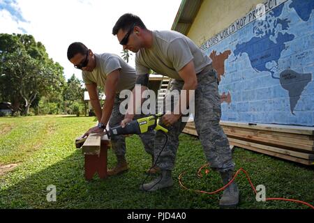 U.S. Air Force Staff Sgt. Alex Estrada, a structural journeyman with the 152nd Civil Engineer Squadron, Nevada Air National Guard, and Senior Airman William Gilson, a structural journeyman with the 374th Civil Engineer Squadron, Yokota Air Base, Japan, cut wood to build benches at Tata Primary and Secondary School during Pacific Angel 18-3 in Luganville, Espiritu Santo Island, Vanuatu, July 14, 2018. During the exercise, U.S. and Vanuatuan service members worked together, in partnership with local non-governmental organizations, to provide humanitarian assistance to the residents of the subdiv Stock Photo