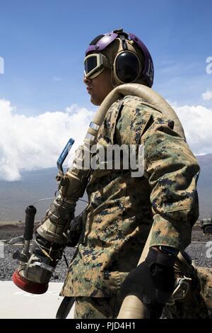 POHAKULOA TRAINING AREA, Hawaii (July 18, 2018) U.S. Marine Corps Lance Cpl. Alexjandro Sanchez-Delarosa, a bulk fuel specialist with Marine Wing Support Detachment 24, stands by to fuel a helicopter at a forward arming and refueling point during a field test for an Expeditionary Mobile Fuel Additization Capability system as part of Rim of the Pacific (RIMPAC) exercise at Pohakuloa Training Area, Hawaii, July 18, 2018. RIMPAC provides high-value training for task-organized, highly capable Marine Air-Ground Task Force and enhances the critical crisis response capability of U.S. Marines in the P Stock Photo