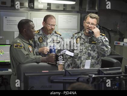 PEARL HARBOR, Hawaii (July 16, 2018) Left to right, Rear Adm. Cedric Pringle, commander, Expeditionary Strike Group (ESG) 3, Royal Australian Navy Capt. Paul O’Grady, , and Commodore Ivan Ingham, commander, Combined Task Group 176, discuss over the phone the upcoming exercises with Chilean Navy Commodore Pablo Niemann, combined forces maritime component commander for the 2018 Rim of the Pacific (RIMPAC) exercise during a battle update briefing in the Joint Operations Center of the amphibious assault ship USS Bonhomme Richard (LHD 6). Twenty-five nations, 46 ships, five submarines, about 200 ai Stock Photo