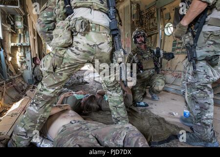 Battlefield Airmen assigned to the 52nd Expeditionary Rescue Squadron treat role players' simulated wounds as part of an aircraft crash scenario during a combat search and rescue training exercise at a dirt landing strip in Iraq, July 15, 2018. Air Force Central Command's expeditionary rescue squadrons are organized, trained, equipped, and postured to conduct full spectrum personnel recovery to include both conventional and unconventional combat rescue operations within the Central Command theater of operations. Stock Photo