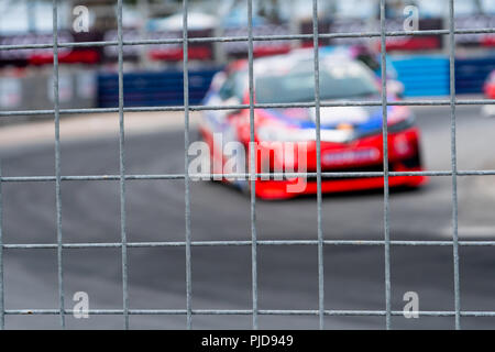 Motorsport car racing on asphalt road. View from the fence mesh netting on blurred car on racetrack background. Super racing car on street circuit. Au Stock Photo