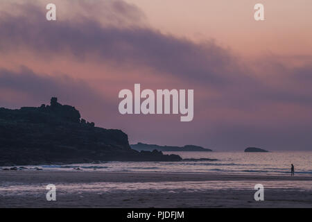 St. Ives, England -  May 2018 : Lonely walker on the Porthmeor beach at dusk, Cornwall,  UK Stock Photo