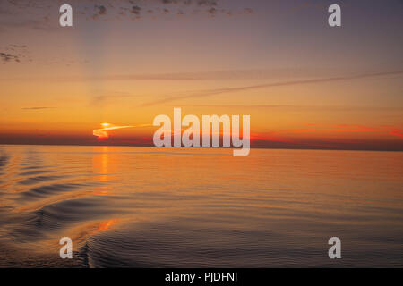 Sunset over the Baltic  sea -  Wake ripping out over an exceptionally calm sea. Stock Photo