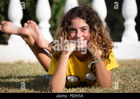 10 year old girl posing lying in the garden of her house and playing with her legs Stock Photo