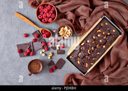 delicious chocolate pound cake from gluten free buckwheat flour with nuts and raspberries in a metal baking mold on a concrete table with cup of coffe Stock Photo