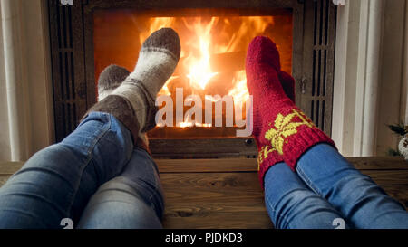Closeup image of romantic couple and jeans and woolen socks warming by the burning fire at house Stock Photo