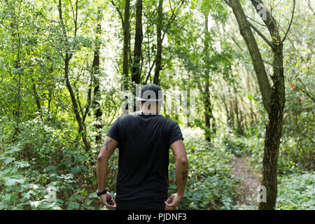 Young guy casually walking through forest on a beautiful day. Stock Photo