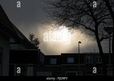 Sun burning a hole in heavy cloud cover during the winter months. Stock Photo