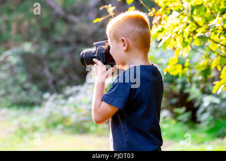 Young boy learning photography with his first DSLR in the woods. Stock Photo