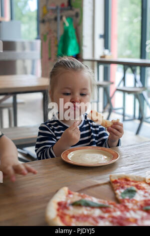 Cute little funny 2 years girl eating pizza in the restaurant Stock Photo