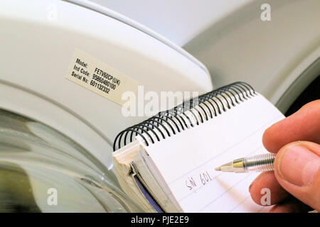 Writing down the manufacturer's serial and model numbers on the inside of a tumble dryer door Stock Photo