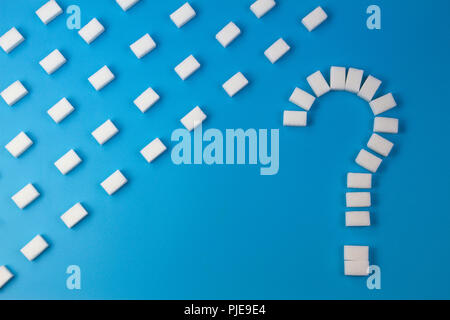 Sugar cubes shaped as a question mark sign on blue background. Stock Photo