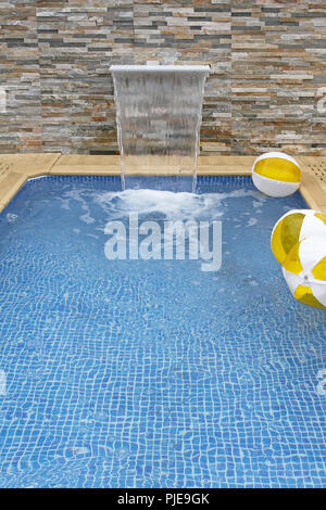 Small modern swimming pool with artificial waterfall Stock Photo