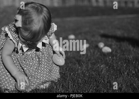 Little girl picking up easter eggs. Black and white photo. Stock Photo
