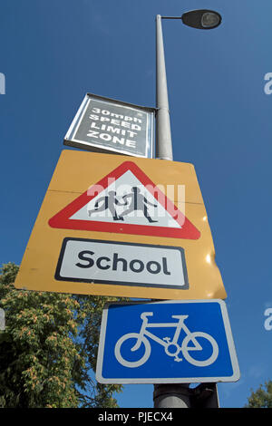 british road signs indicating a school with children crossing the road a 30mph speed limit, and a cycle route, in surbiton, surrey, england Stock Photo