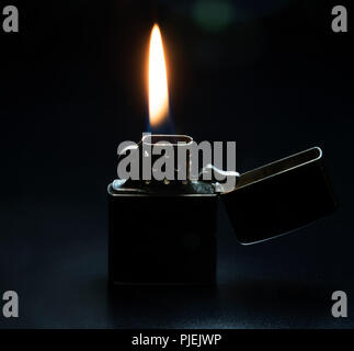 Zippo lighter with yellow flame isolated on black background. Stock Photo