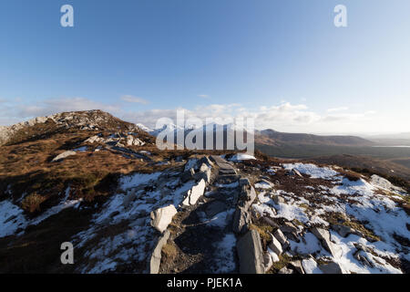 Summit of Diamond Hill in Connemara National Park in winter overlooking the snowcapped mountains of The Twelve Bens. Stock Photo