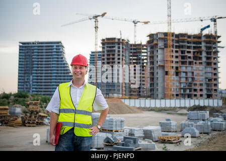 Engineer looking at camera on a construction site wearing reflective west working on housing project Stock Photo