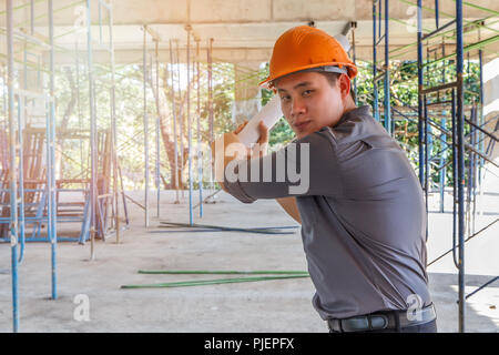 The architect relaxes by acting as a baseball player. Engineer with blueprint in building construction site Stock Photo
