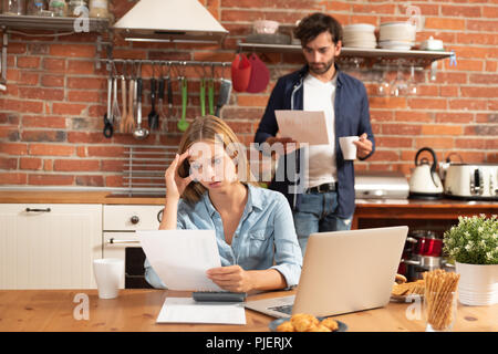 Young couple in savings and home budget concept. Managing finances, taxes using calculator and laptop. Stock Photo