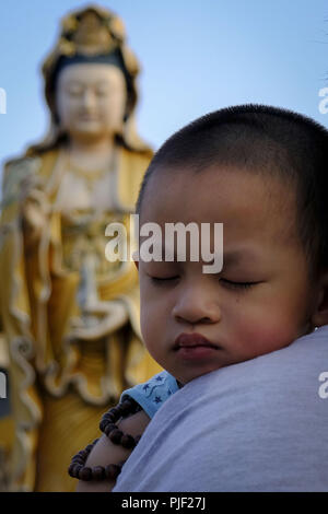 Kuala Lumpur, Klang, Malaysia. 26th Aug, 2018. A little boy seen on a nap during the hungry ghost festival at a temple in Klang.Hungry ghost festival were celebrated at Malaysia on the 7th month of Chinese calendar by the Buddhist, Taoist and also since the Chinese ancient religion has believe the gate of hell will be open for the hungry ghost to seek food an entertainment on the world. According to their understanding the hungry ghost can emerge from neglect or desertion of ancestor and also from the violent and unhappy death. Usually the devotee families will offer prayers to their dece Stock Photo