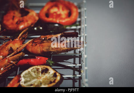 Fresh grilled prawn shrimps on metal grid and grey background Stock Photo