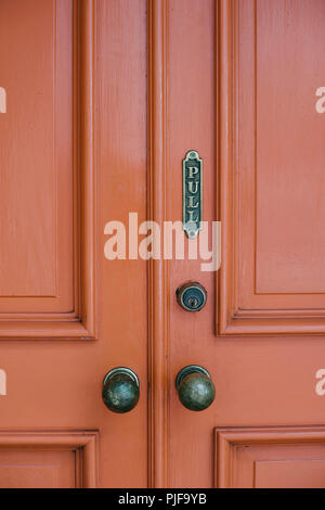 Red doors with ornate framing, old knobs and a pull sign Stock Photo