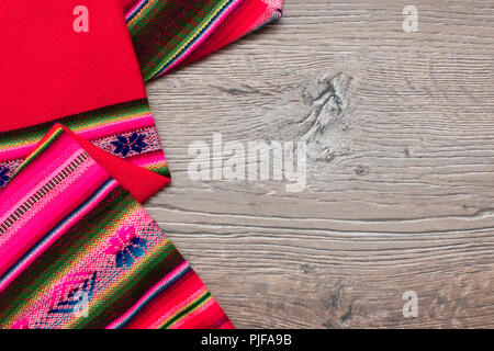Natural background of thick multicolor patterned tablecloth on dark wooden table. Fabric texture  for background. Top view. Copy  space for your text Stock Photo