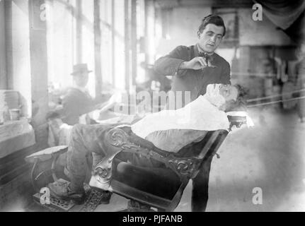 Barber, historic image of a barber giving a shave to a man, circa 1915 Stock Photo