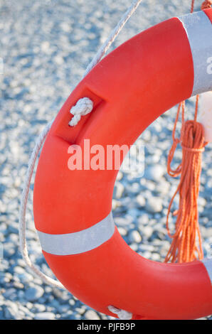 Lifebuoy at the pier. Red life ring with rope on the pier near the sea, outdoors. Stock Photo