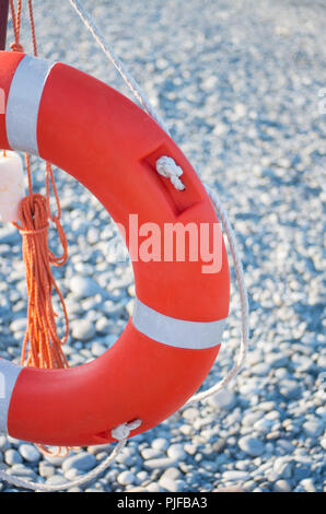 Lifebuoy at the pier. Red life ring with rope on the pier near the sea, outdoors. Stock Photo