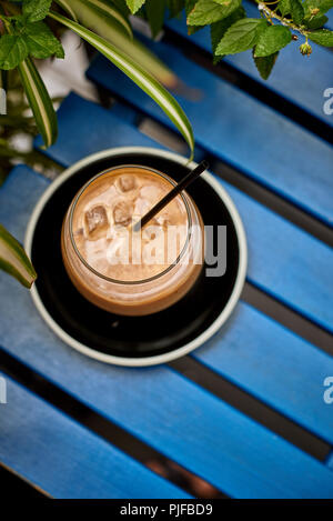 Cold coffee drink in the glass on the blue wooden table Stock Photo