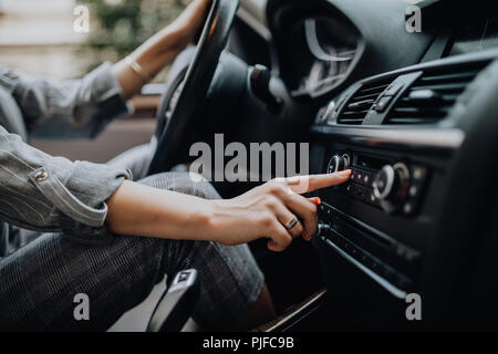 Car dashboard. Radio closeup. Woman sets up radio Stock Photo