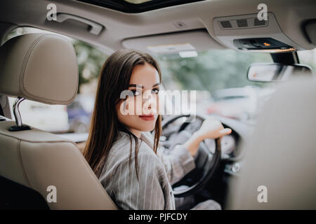 woman in car indoor keeps wheel turning around smiling looking at passengers in back seat idea taxi driver talking to police companion companion who a