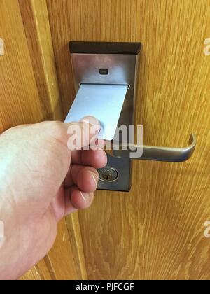 A POV of a human hand using a hotel or motel key card in a room door lock Stock Photo