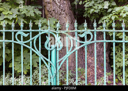 old metal decorative garden fence painted blue with paint peeling off Stock Photo