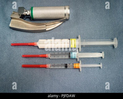 Three labeled anesthesia drugs, propofol, fentanyl and midazolam, on a gray blue towel from above. Stock Photo