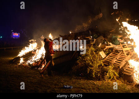 Bonfire night celebrations in Littlehampton, West Sussex, England, UK. A man throws a flaming torch onto a large bonfire. Stock Photo